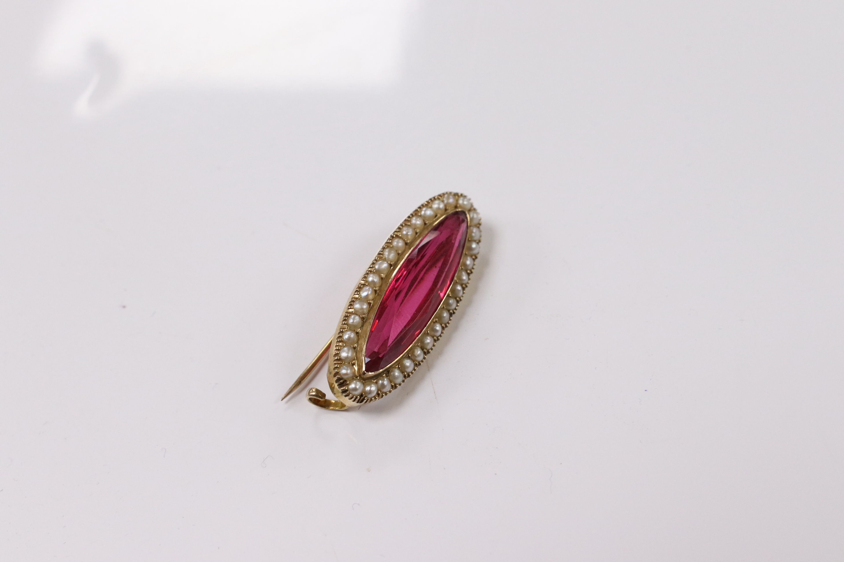 A 9ct, red paste and seed pearl set navette shaped brooch, 31mm, gross weight 4.2 grams. Condition - good